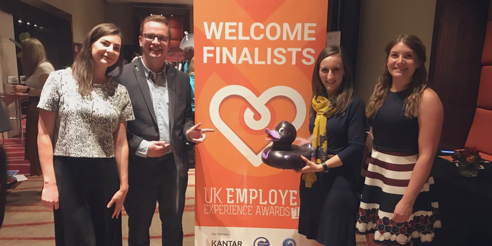 Group of people standing in front of a pop up banner at the employee experience awards