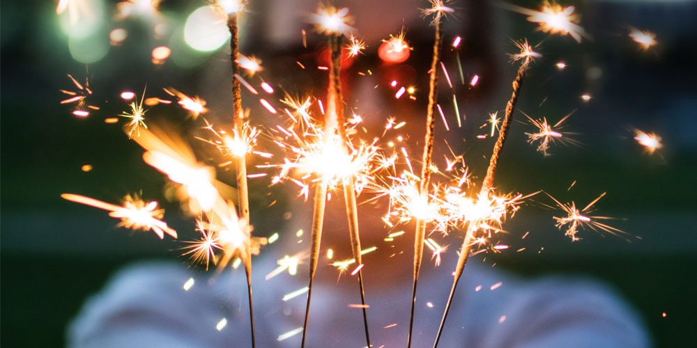 Lady holding sparklers in her hands|People standing in running gear with race numbers on them