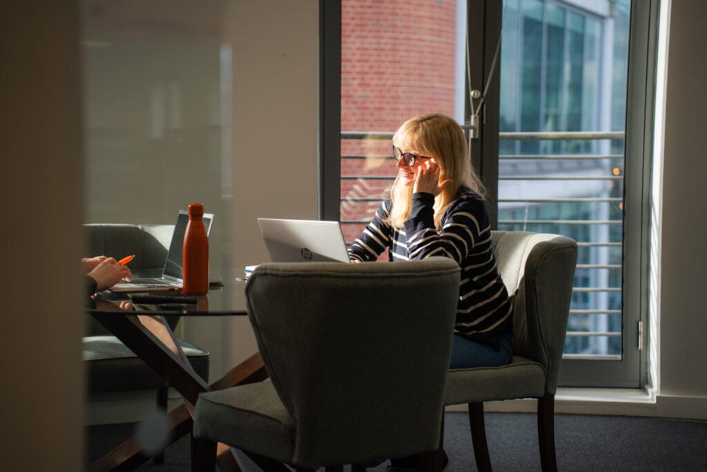 Woman sitting at desk in office in meeting room smiling