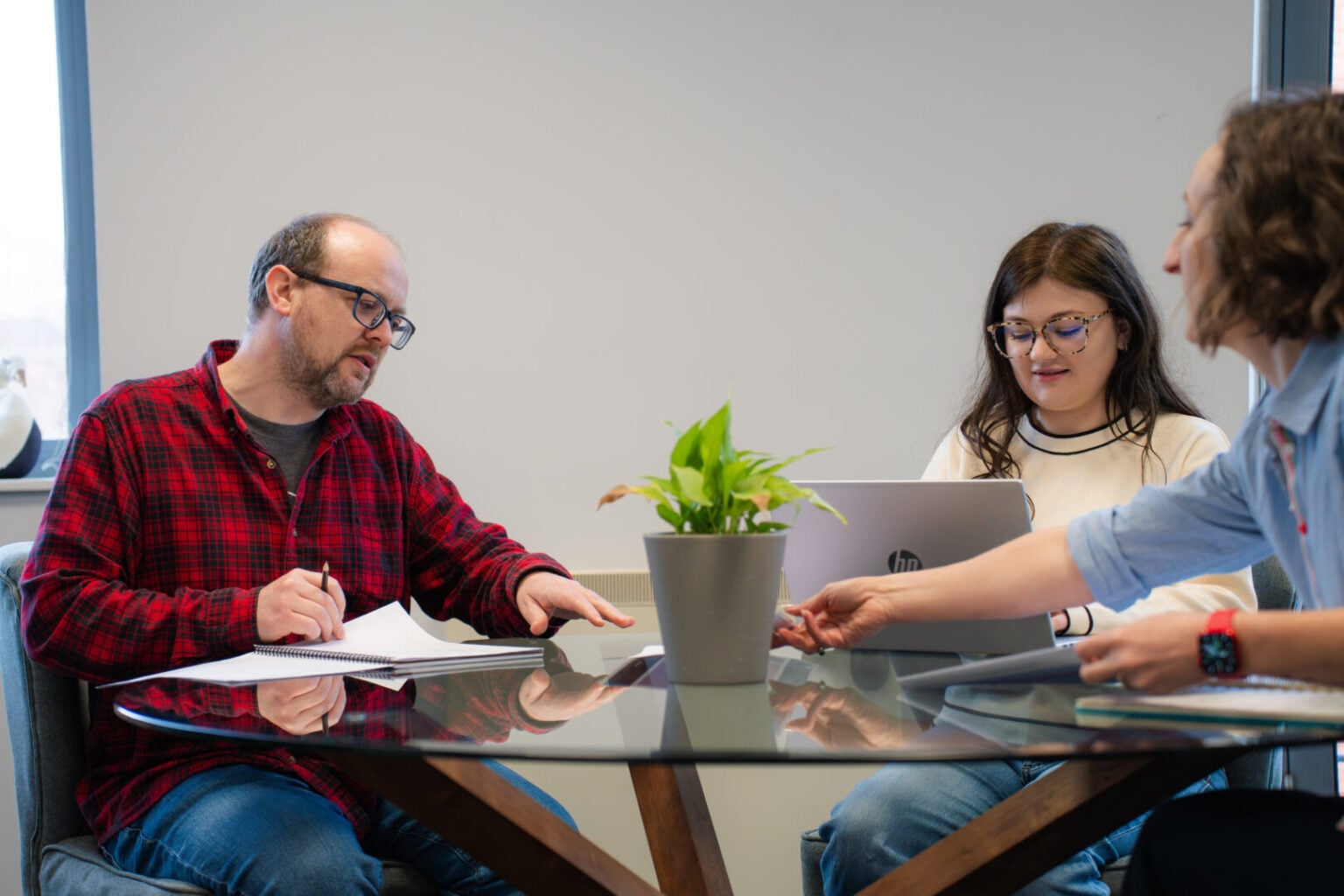 two women and one man up a desk, with laptop and paperwork